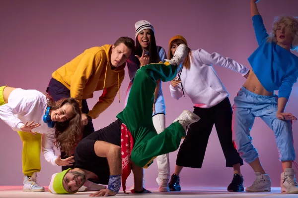Group of dancers on dancing festival Sportive hip hop dancer standing on head, looking at camera, expressing cheerful expression, leaning on hands, active people surrounding break dancer performing on floor