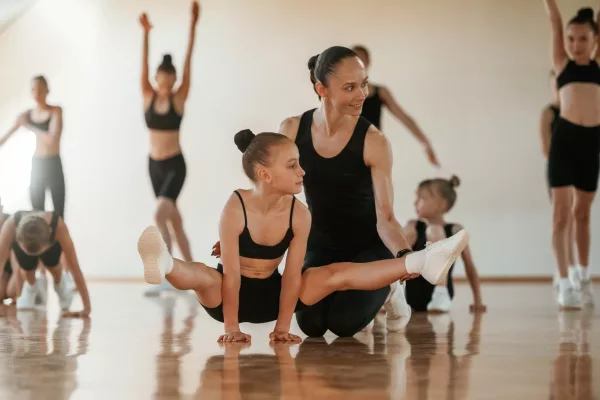 Professional coach is helping. Group of female kids practicing athletic exercises together indoors Professional coach is helping. Group of female kids practicing athletic exercises together indoors.